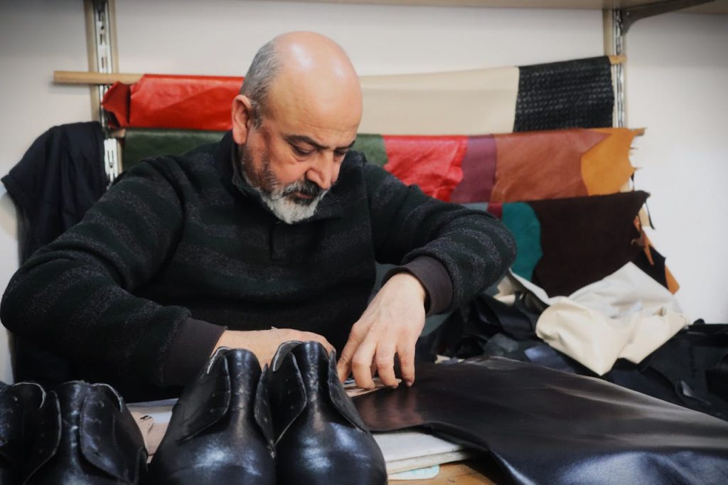 Shoemaker meticulously crafting leather shoes in a small business workshop. Showcasing traditional craftsmanship and skill.
