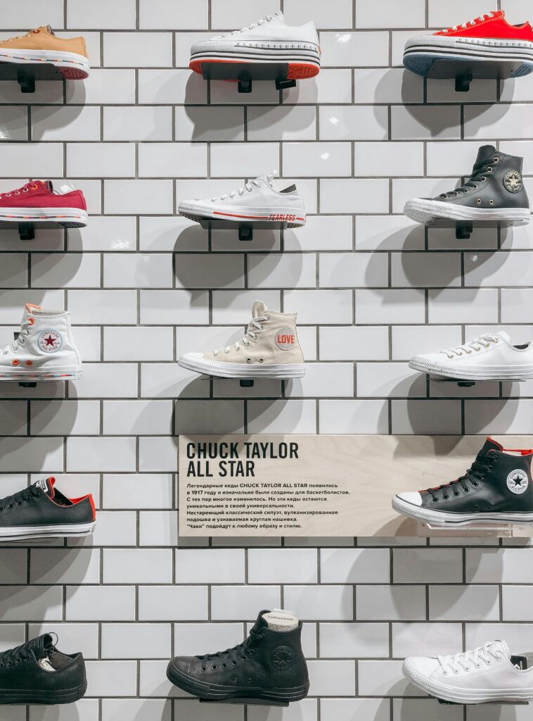 A selection of Chuck Taylor sneakers displayed on a tiled wall in a store.