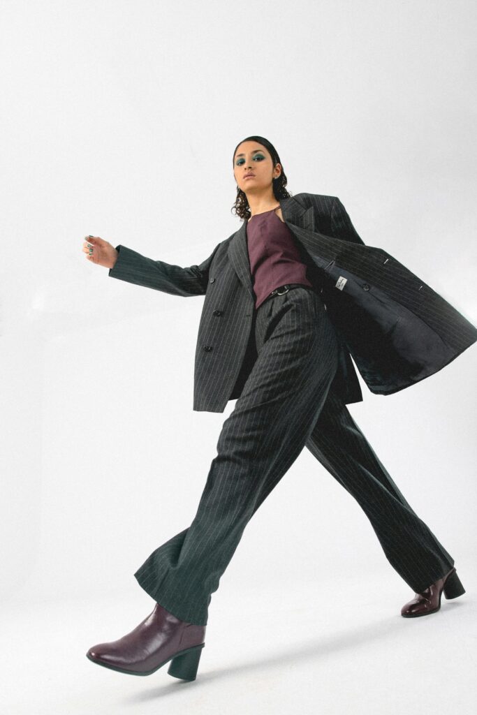 pexels-photo-8661807-8661807 Fashion model poses dynamically in a stylish pinstripe suit with bold makeup.