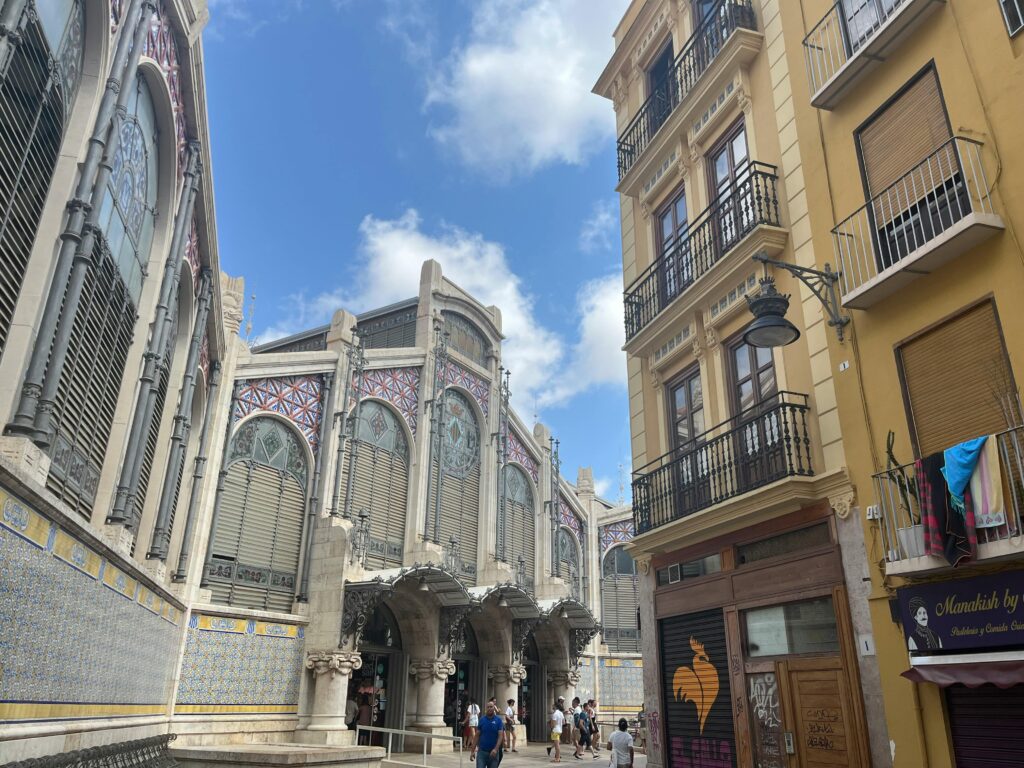 pexels-photo-27796191-27796191 Street view of València's Central Market with historic buildings under a blue sky.